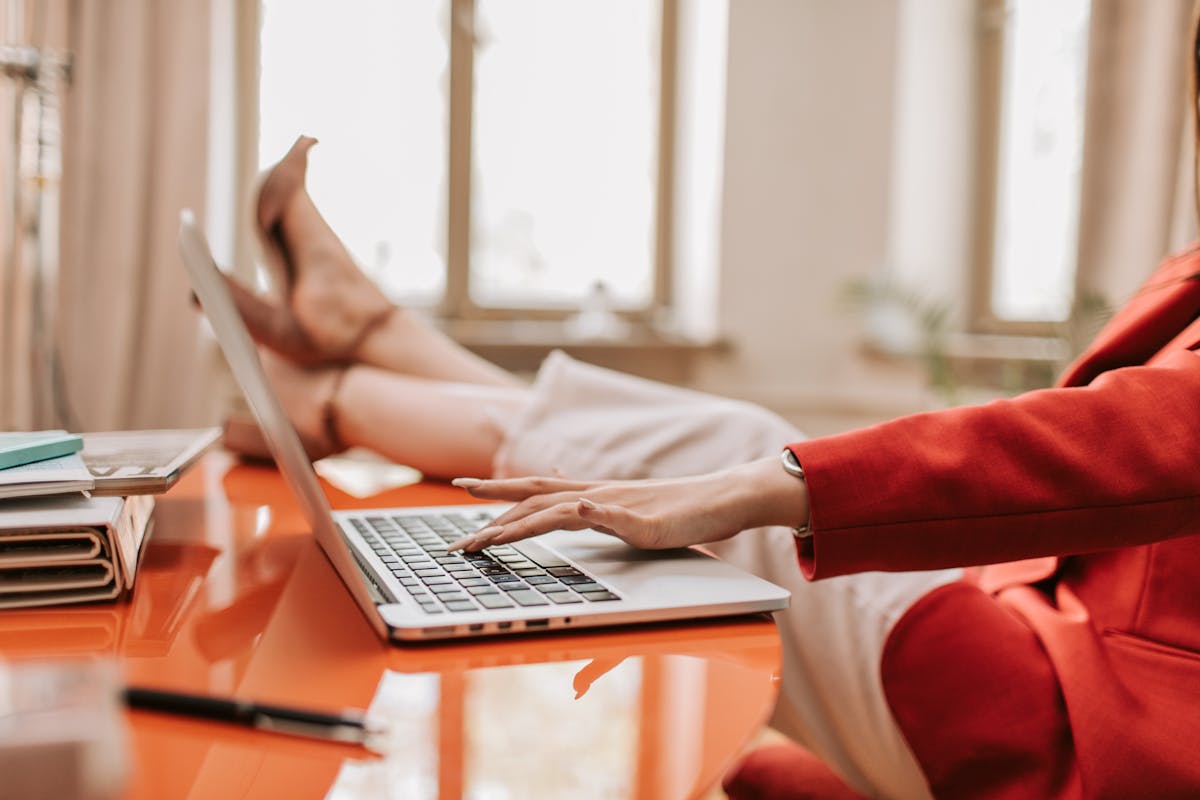 ノートPCの前で足を組むデスクワーク女性