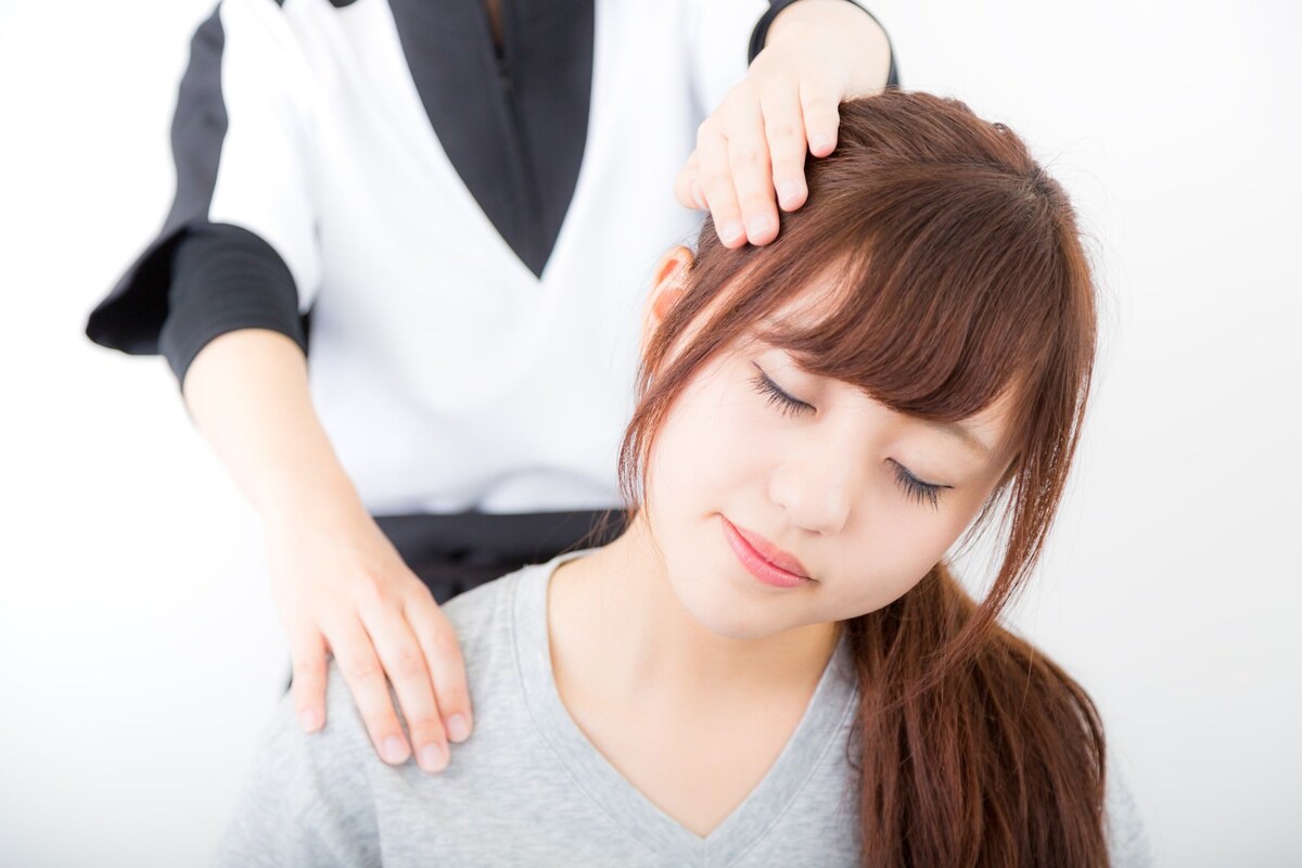女性施術者が女性のお客様の首と肩甲骨まわりを丁寧にケアしている整体シーン