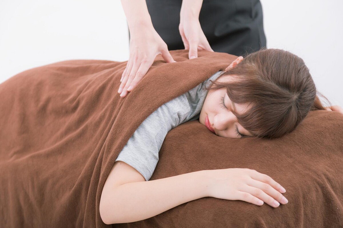 うつ伏せで腰・背中への整体施術を受ける女性
