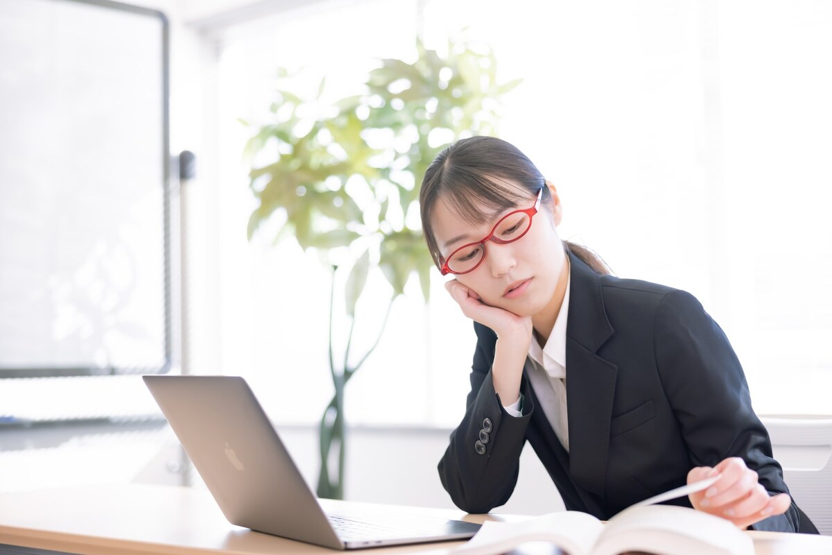 冷房の効いたオフィスでデスクワークをする30代女性