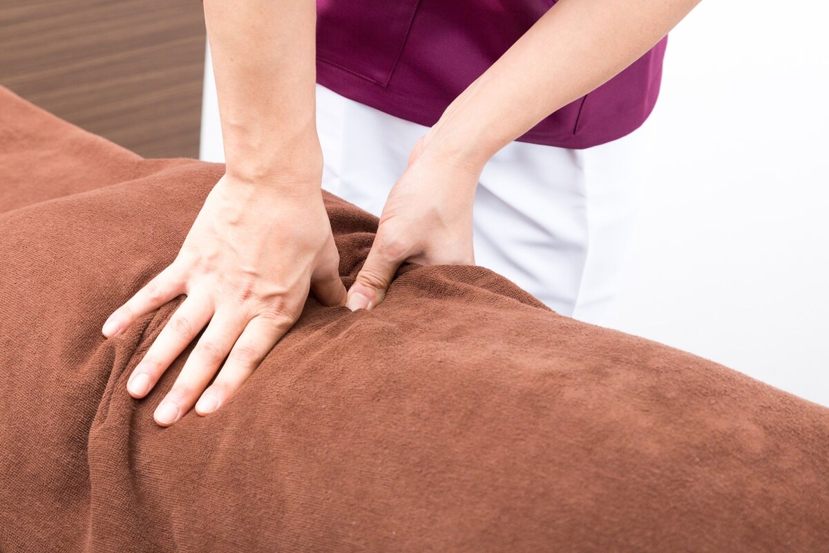 冷房の効いたオフィスで腰の重さに悩む30代女性が施術を受けるイメージ